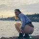A pretty blonde girl squats along the Seattle seashore outdoors while pissing and shitting in public view. The Space Needle is seen in he background. Presented in 720P HD. About half a minute.